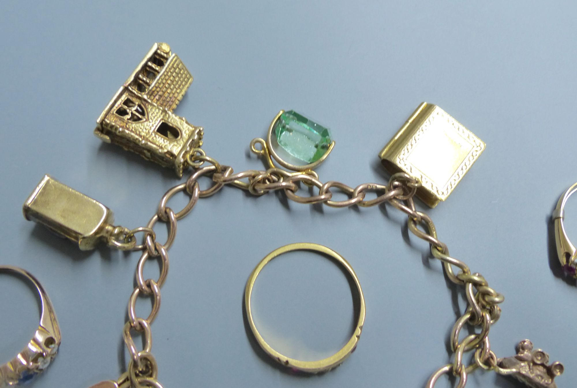 A 9ct gold charm bracelet, hung with six assorted charms including 9ct gold and 3 rings.